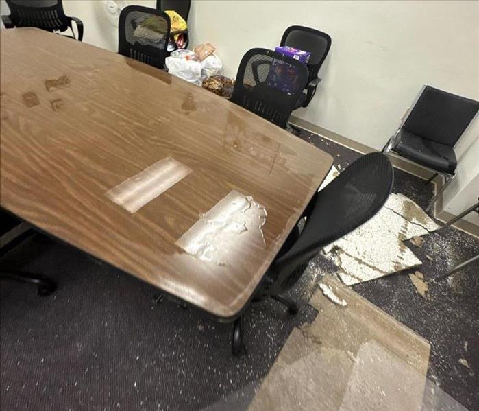 Water damage in a conference room with table and chairs and ceiling debris from damage